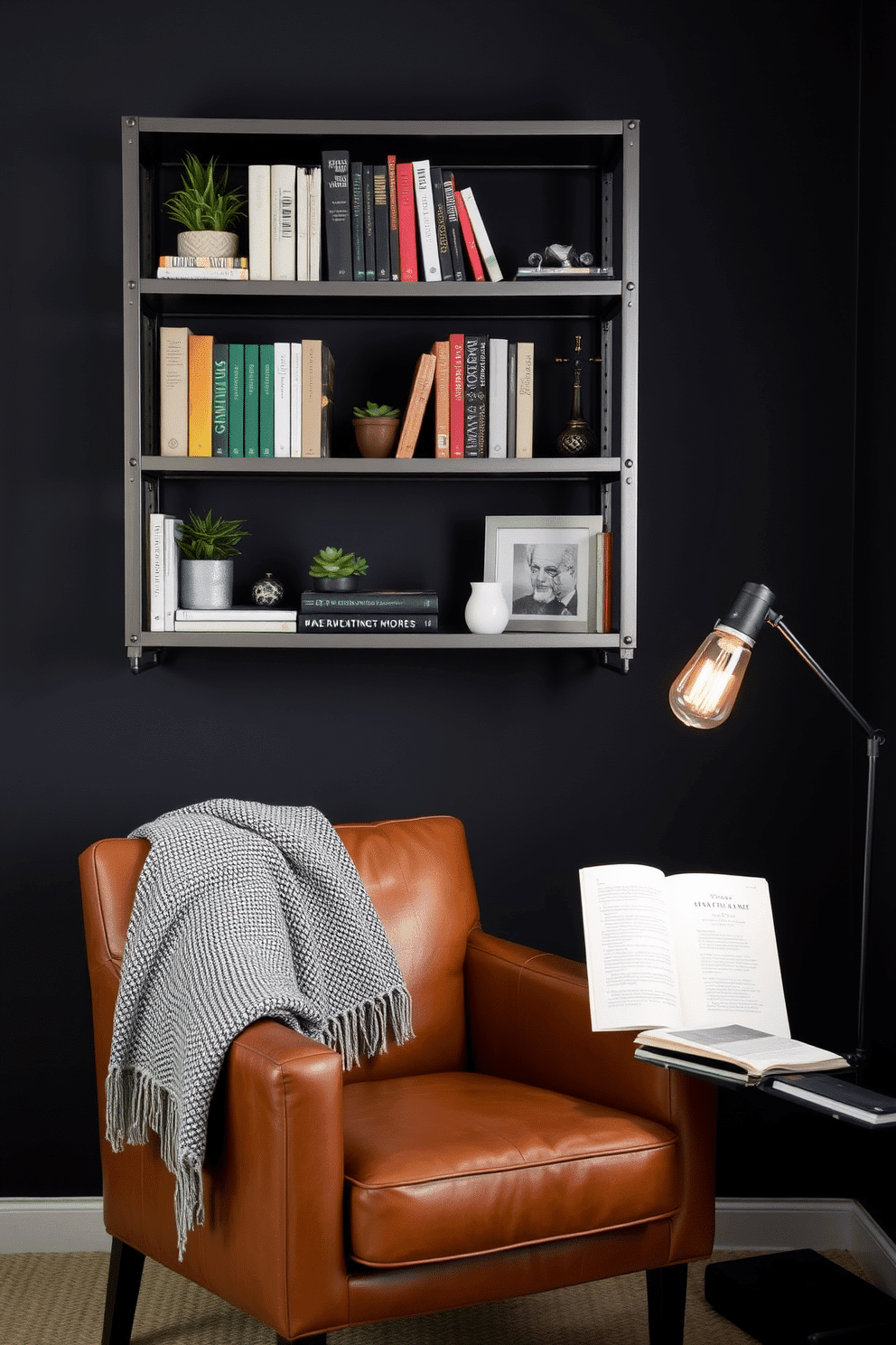 An industrial-themed bedroom reading nook features sleek metal shelves with rivet details, filled with books, potted greenery, and decorative trinkets. A cognac leather armchair with clean lines sits nearby, complemented by a textured throw blanket draped over one arm. The walls are painted in a deep charcoal hue, creating a cozy yet contemporary atmosphere. A vintage-style floor lamp with a warm Edison bulb sits by the chair, casting a soft glow perfect for evening reading sessions.