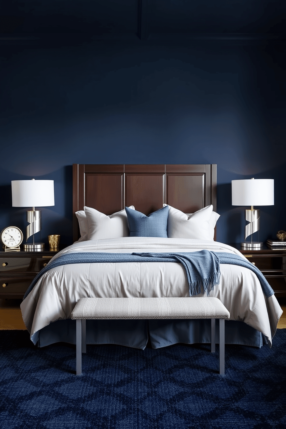 A stately blue bedroom with a masculine touch. The walls are painted in a deep navy tone, complemented by soft gray bedding and accent pillows. A tall, dark wood headboard anchors the bed, paired with sleek, silver-toned table lamps on matching nightstands. A textured navy area rug rests underfoot, while subtle metallic accents add a refined charm to the space.