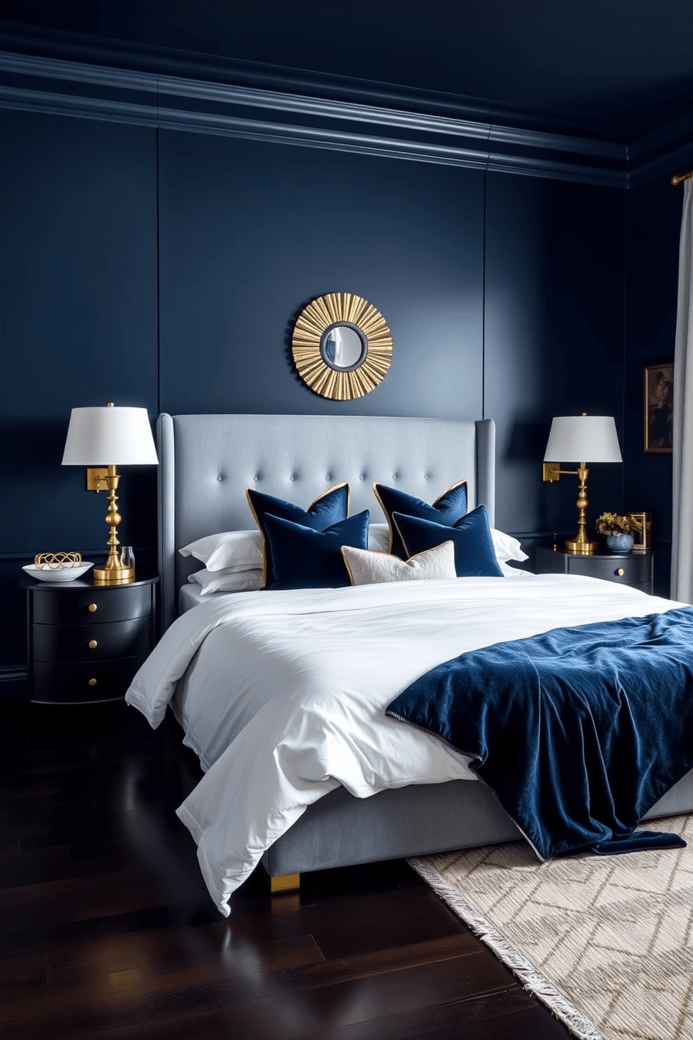 A deep midnight blue envelops the bedroom walls, creating a dramatic and luxurious retreat. A plush upholstered headboard in a lighter shade of dusty blue stands against the wall, complemented by crisp white bedding layered with rich navy throw pillows and a velvet blanket. Warm gold accents shine through in the bedside lamps and decorative wall art, adding a touch of sophistication to the room. The dark wooden flooring grounds the design, softened by a neutral area rug, while sheer curtains allow soft natural light to filter through during the day.