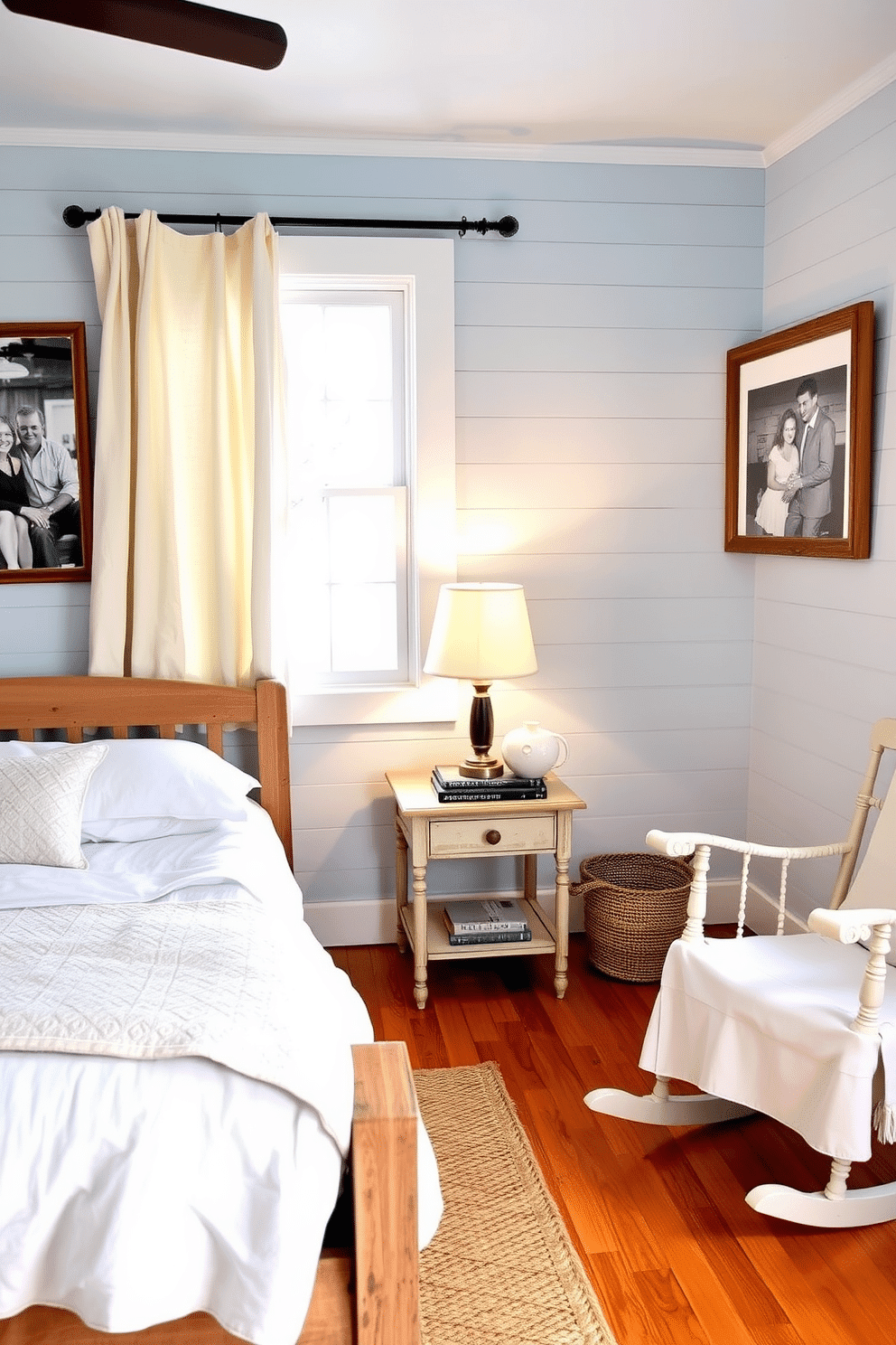 A cozy, rustic bedroom painted in a soft country blue shade, creating a serene and inviting atmosphere. A distressed wood bed frame with white linens is paired with a quilted throw, and a woven rug sits atop the warm, hardwood floors. On the bedside table, a vintage lantern-style lamp casts a gentle glow, alongside a stack of books and a ceramic vase with wildflowers. The shiplap walls are adorned with black-and-white family photographs in weathered wooden frames, while a charming rocking chair rests beside a window with billowing linen curtains.