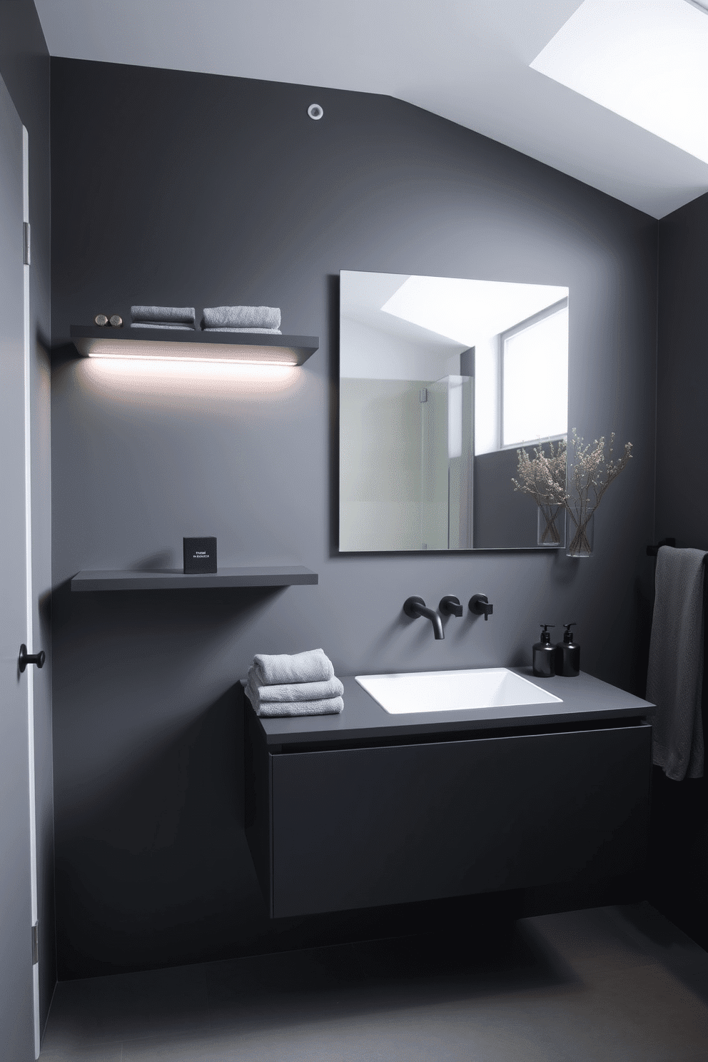 A contemporary bathroom featuring graphite-colored floating shelves paired with a sleek floating vanity. Subtle under-cabinet lighting illuminates the space, while matte black fixtures add a modern touch. The walls are painted in a smoky gray hue, creating a seamless, monochromatic backdrop. A large frameless mirror reflects light, complemented by soft gray towels and minimalist decorative accents.
