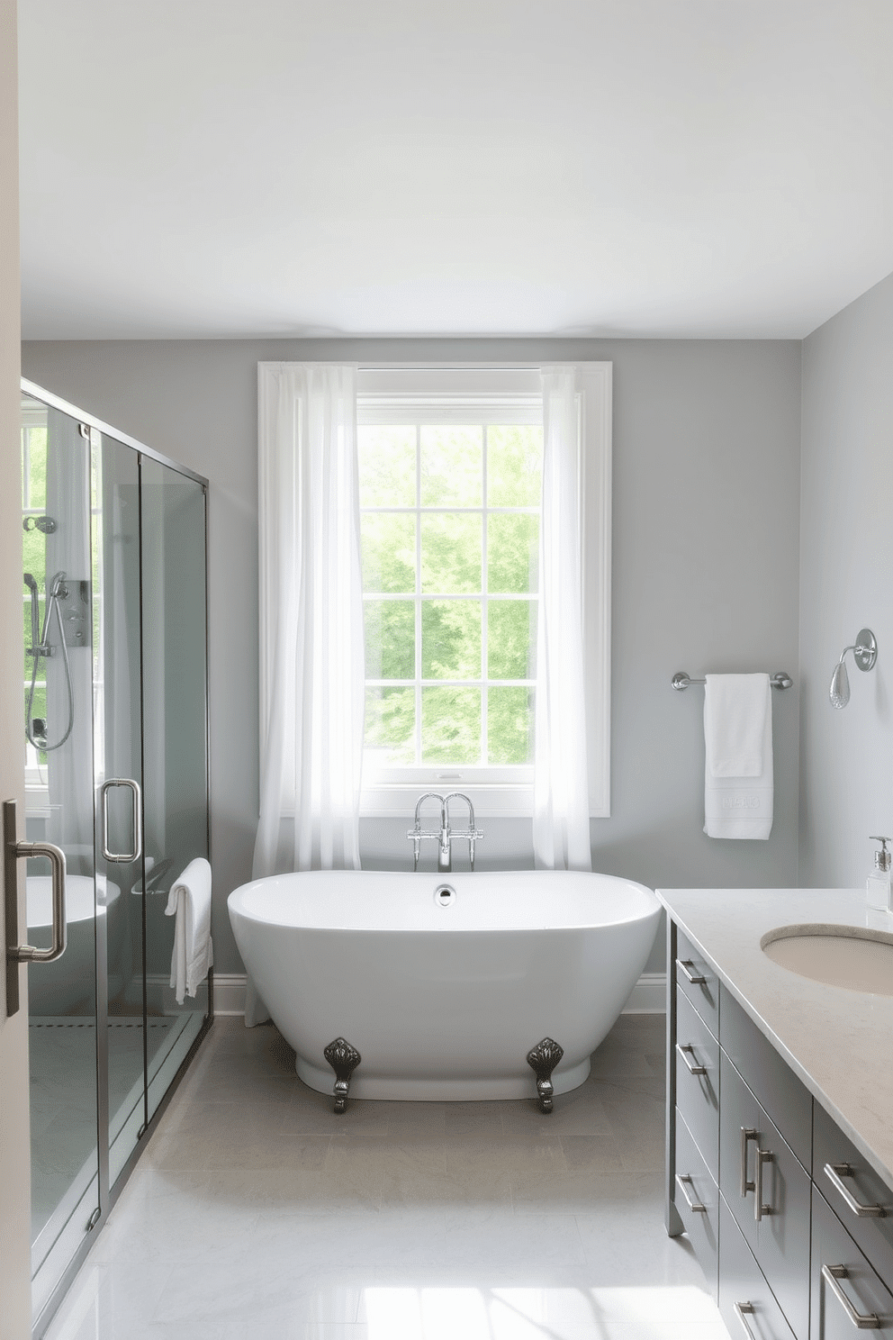 A serene bathroom with pale gray walls creates a neutral and calming backdrop. Chrome accents, including sleek faucets, a modern towel rack, and a frameless shower door, add a touch of contemporary luxury. A freestanding white tub is centered under a large window with sheer white curtains that softly diffuse the light. Polished gray floor tiles and a matching gray vanity with quartz countertops complete the cohesive and elegant design.