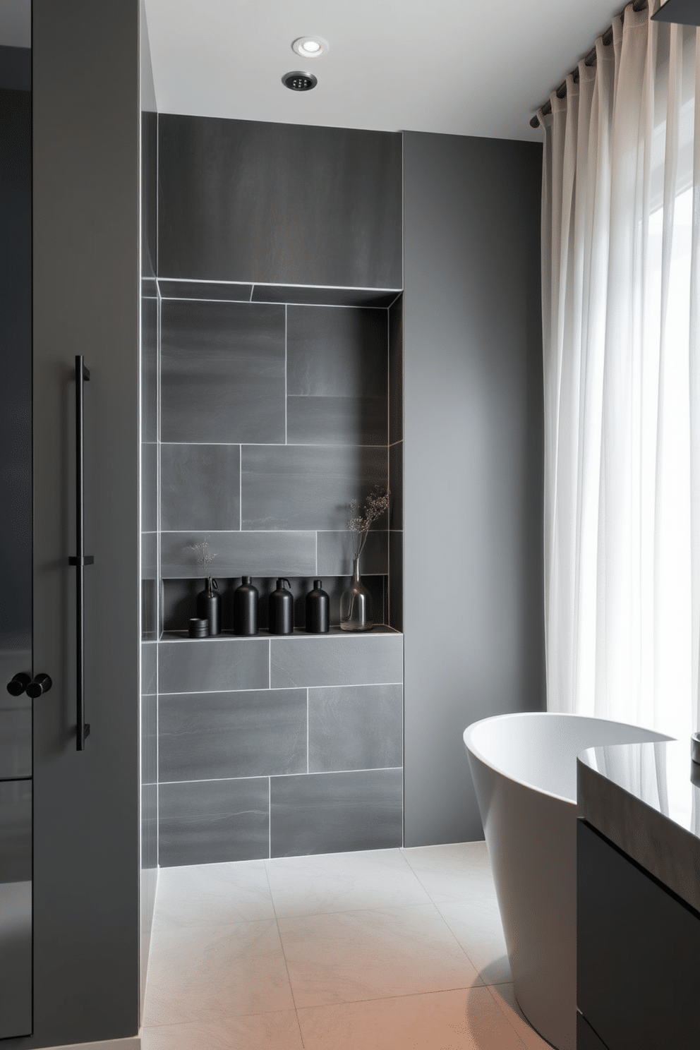 A sleek and modern bathroom with slate gray tiles covering the shower niche, providing a sophisticated backdrop. The niche is neatly divided into compartments, holding minimalistic matte black bottles and subtle greenery for added texture. To complement the shower niche, the rest of the bathroom features gray tones with smooth, polished finishes. A freestanding oval bathtub sits by the window, framed by gauzy, off-white curtains that let in soft natural light.