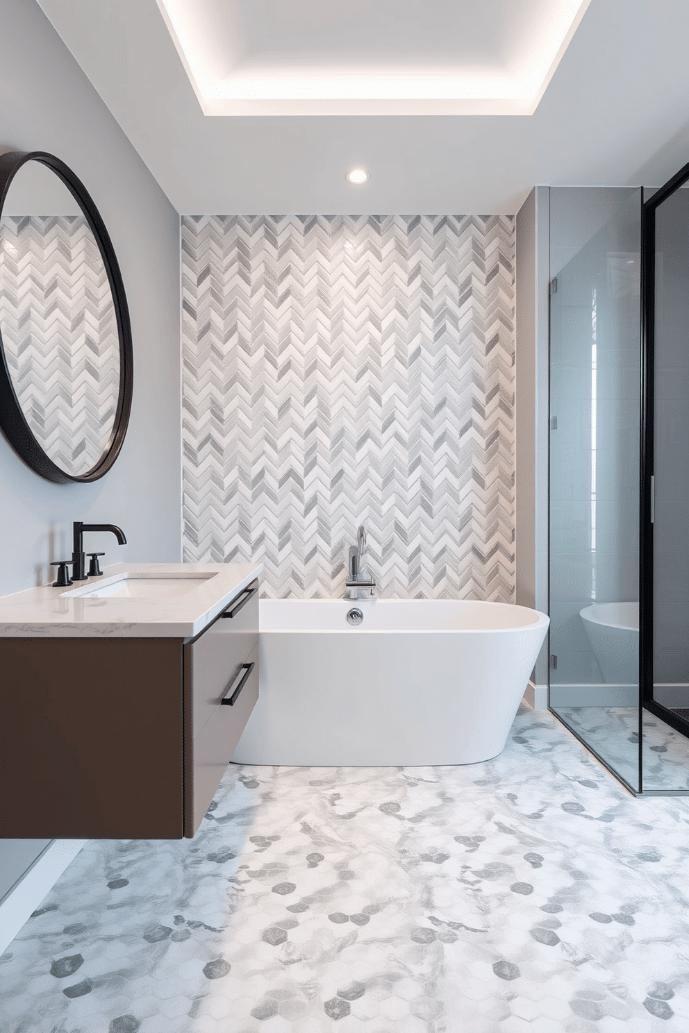A bathroom designed with chevron mosaic tiles that create a striking feature wall behind the bathtub. The soft interplay of white and gray tones in the tiles adds depth and visual interest to the sleek, spa-inspired space. A floating vanity with clean lines is paired with a quartz countertop and an oversized round mirror with a matte black frame. The floor continues the mosaic theme, transitioning seamlessly into larger-scale tile designs in coordinating hues to maintain cohesion.