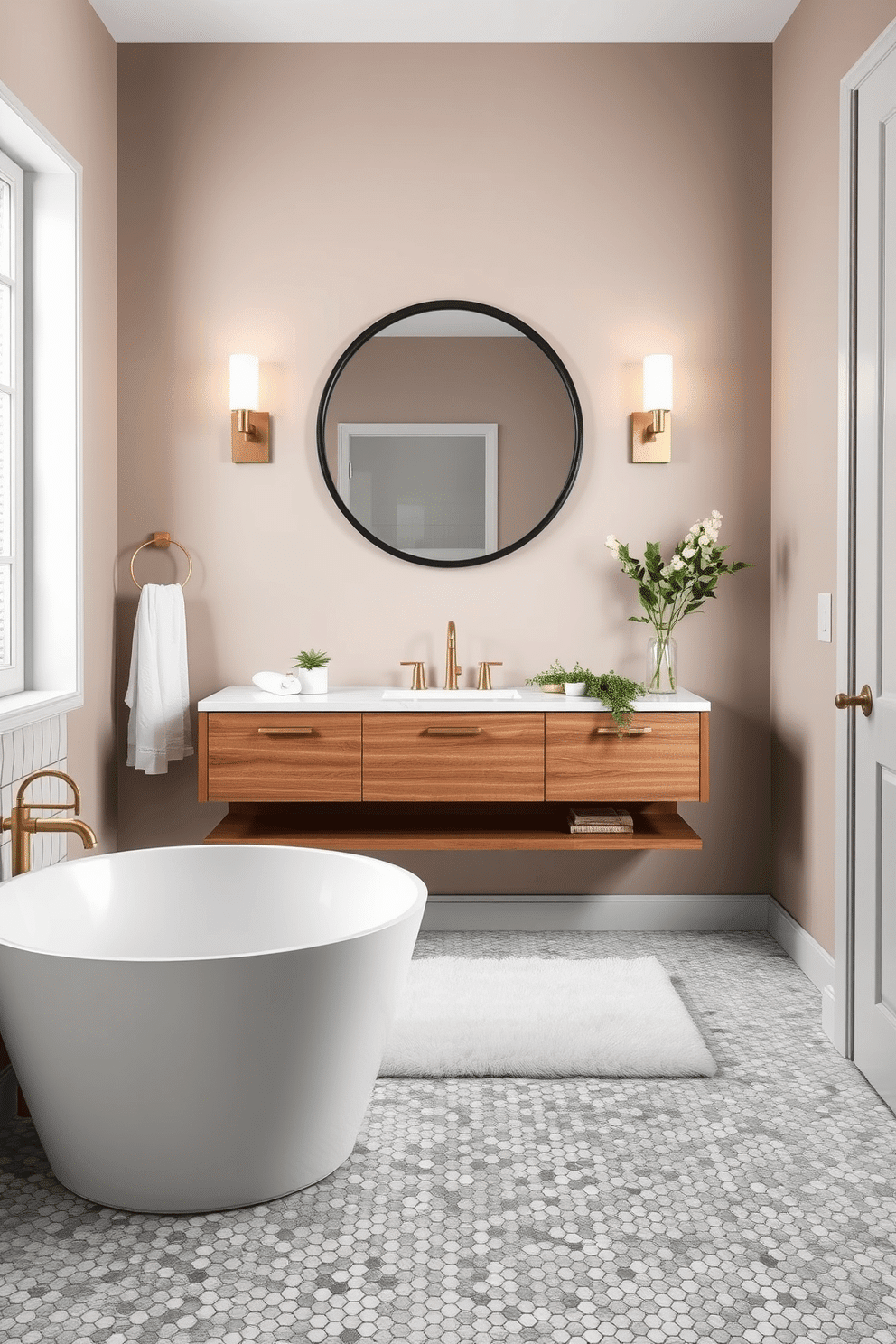A stylish bathroom with faux marble mosaic tiles adorning the floor, creating an elegant and timeless foundation. The walls are painted in a soft taupe shade, complemented by a sleek white freestanding bathtub and brushed brass accents throughout. A floating wooden vanity with a quartz countertop sits beneath a large circular mirror with a matte black frame. Soft lighting from wall sconces enhances the mosaic tile’s intricate pattern, while a plush white rug and fresh greenery add warmth and texture to the space.