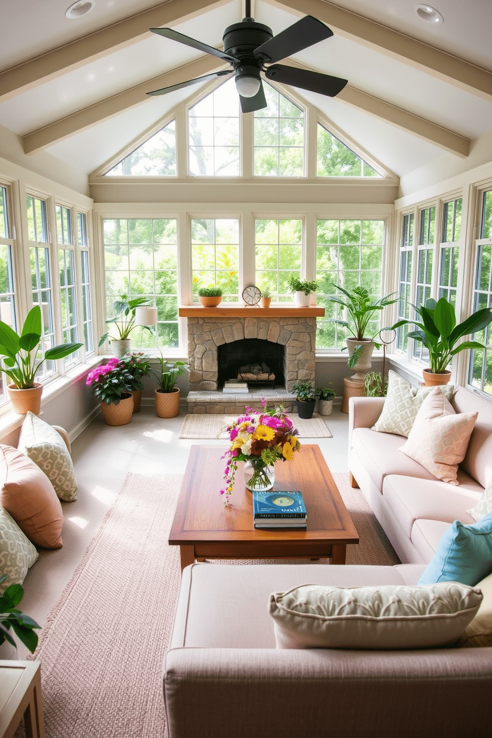 A bright and inviting sunroom filled with natural light. Large windows frame a cozy seating area featuring a plush sectional sofa adorned with pastel throw pillows. In one corner, a stone fireplace adds warmth and charm, surrounded by potted plants and decorative accents. A wooden coffee table sits in the center, topped with a colorful floral arrangement and a few art books.