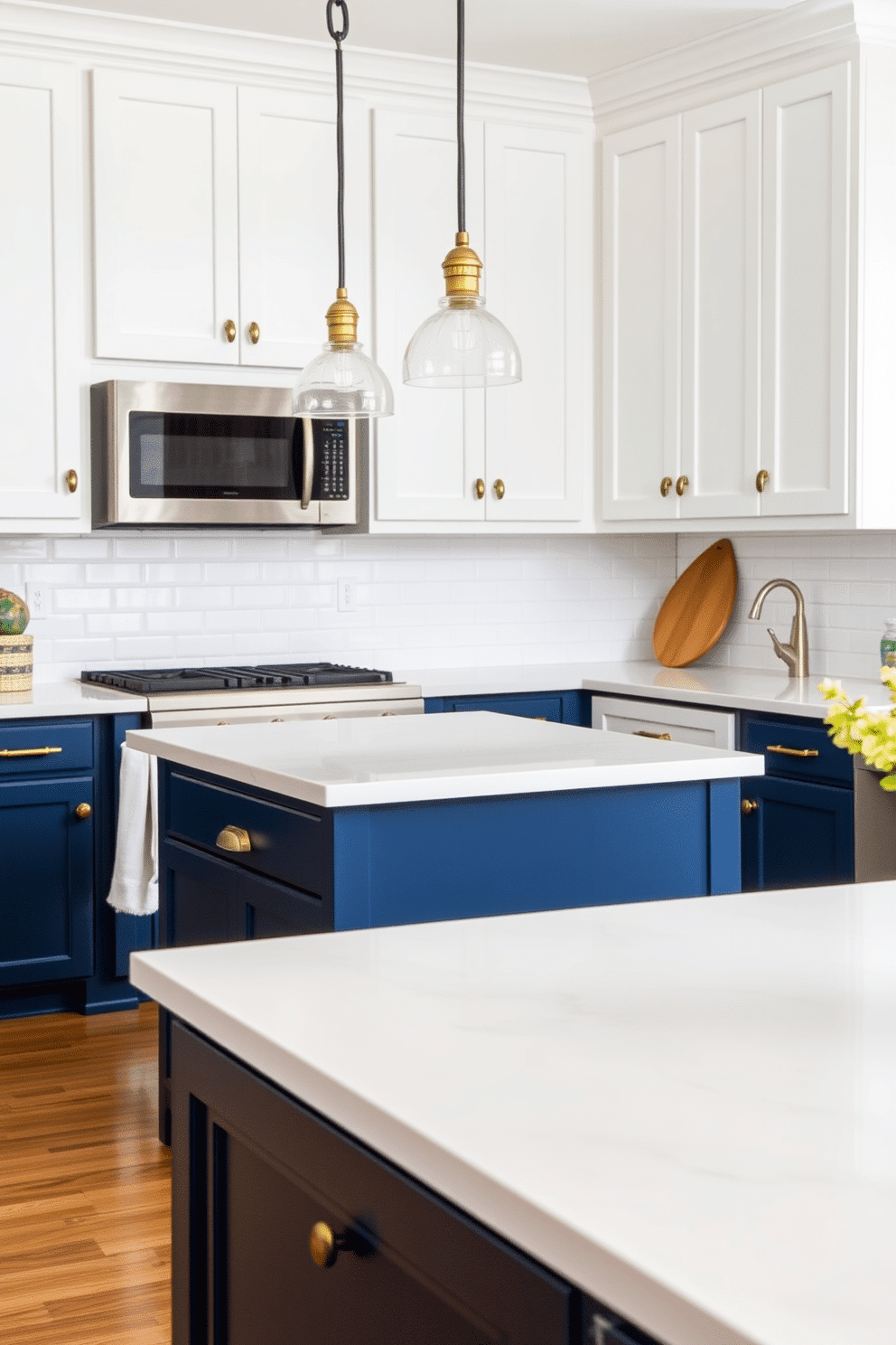 A stylish two-tone kitchen with navy blue base cabinets paired with crisp white upper cabinets, creating a striking contrast. The navy blue island features a sleek white quartz countertop, while the perimeter counters are accented with polished subway tiles in a glossy white finish. Warm brass hardware adorns the cabinets, adding a touch of sophistication to the space. A pair of pendant lights with glass shades hang gracefully above the island, and a natural wood cutting board leans casually against the backsplash for added warmth.