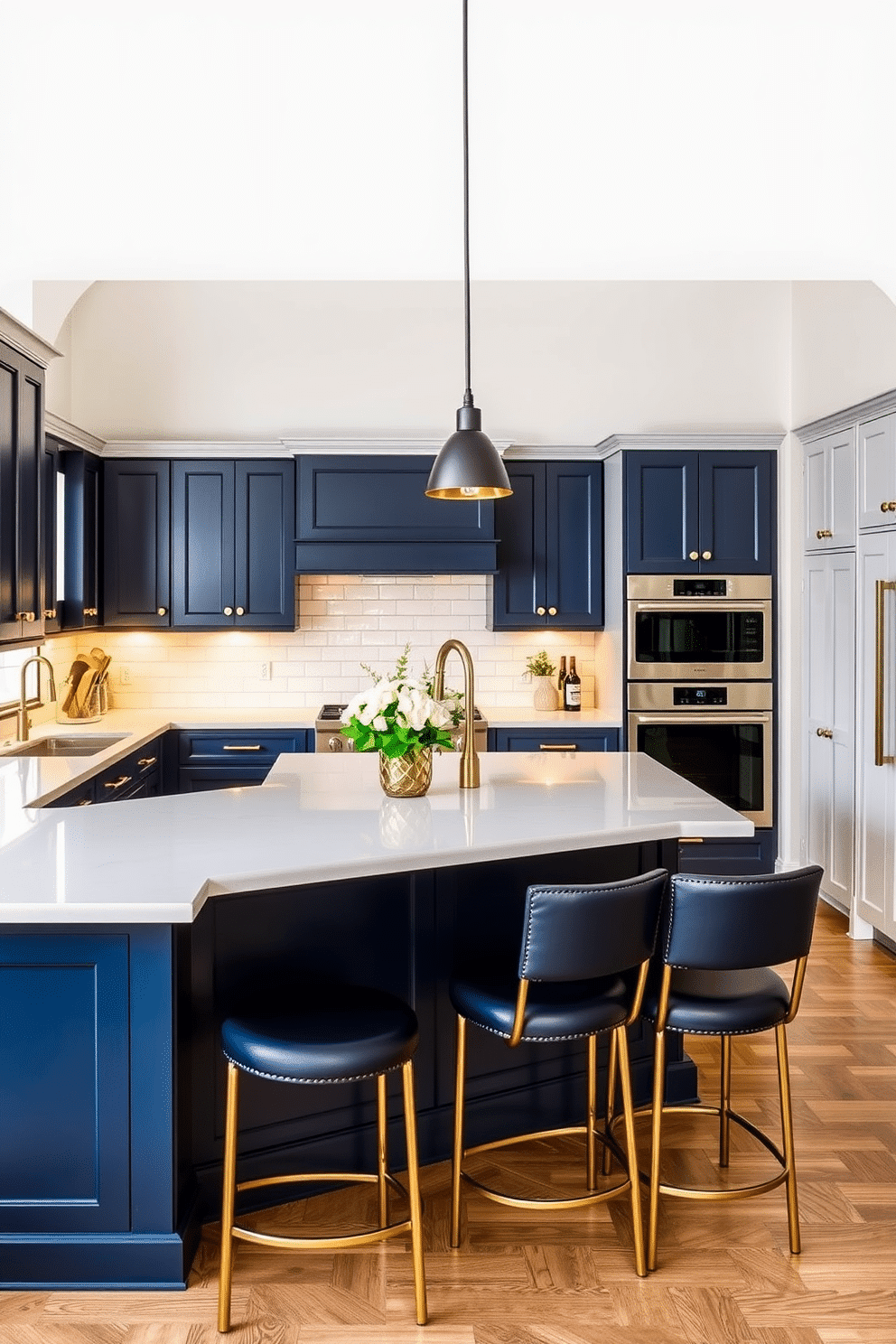 A striking two-tone kitchen featuring rich navy lower cabinets contrasted with pale gray upper cabinets. The countertops are sleek white quartz, and a navy island with golden hardware serves as the focal point of the space. Warm under-cabinet lighting highlights a glossy white subway tile backsplash that runs along the walls. Barstools with navy leather seats and gold accents are neatly tucked beneath the island, while pendant lights with matte black finishes hang above.