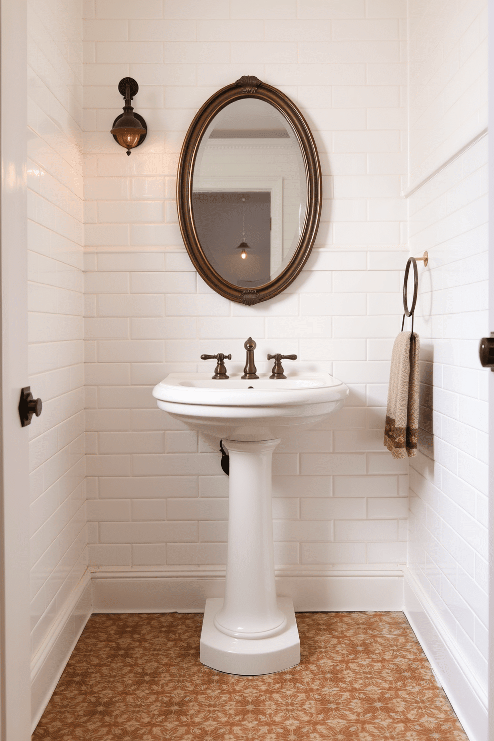 A charming vintage bathroom design featuring a timeless pedestal sink. The sink is accompanied by ornate mosaic flooring in soft earthy tones, adding intricate visual texture beneath. The walls are clad in pale cream subway tiles, providing a clean, classic backdrop. Above the sink, an oval mirror with an antique bronze frame reflects warm ambient lighting from an art deco-style wall sconce.