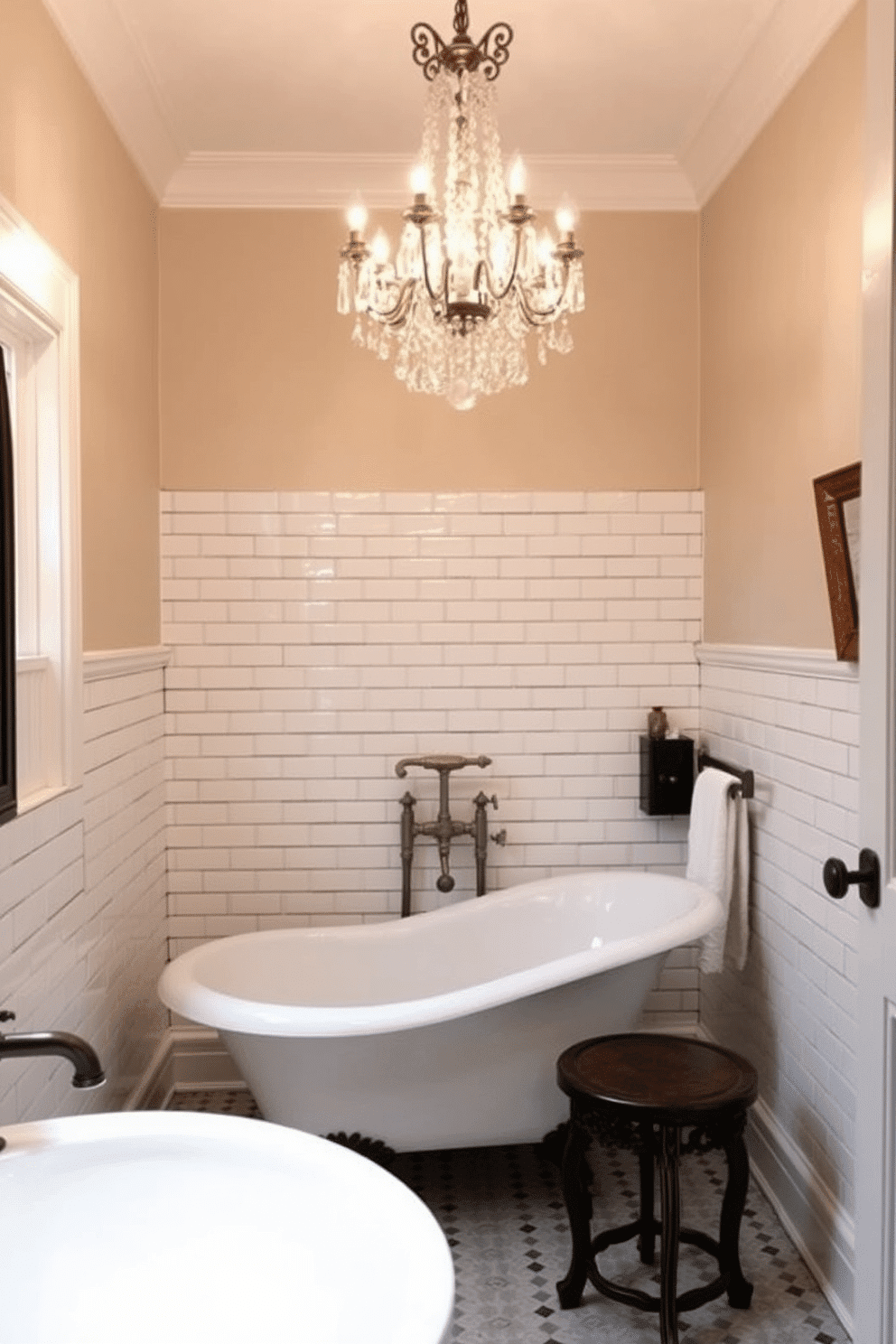 A vintage bathroom adorned with classic charm. A luxurious clawfoot tub takes center stage, beneath an elegant crystal chandelier that casts a warm, ambient glow across the room. The walls are clad in white subway tiles with a dark grout, paired with soft beige-painted upper walls for a timeless contrast. Bronze fixtures and a small, intricately carved wooden stool next to the tub complete the nostalgic atmosphere.
